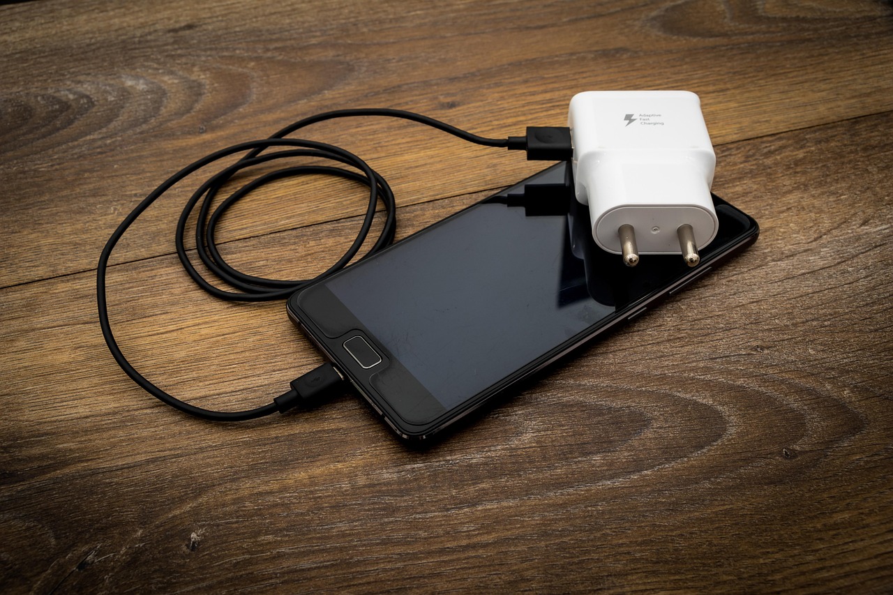 نمای نزدیک یک شارژر USB سفید در کنار کابل، نشاندهنده خطر برقگرفتگی و آتشسوزی